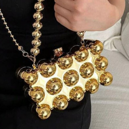 Gold spherical handbag held by a person with a blurred background